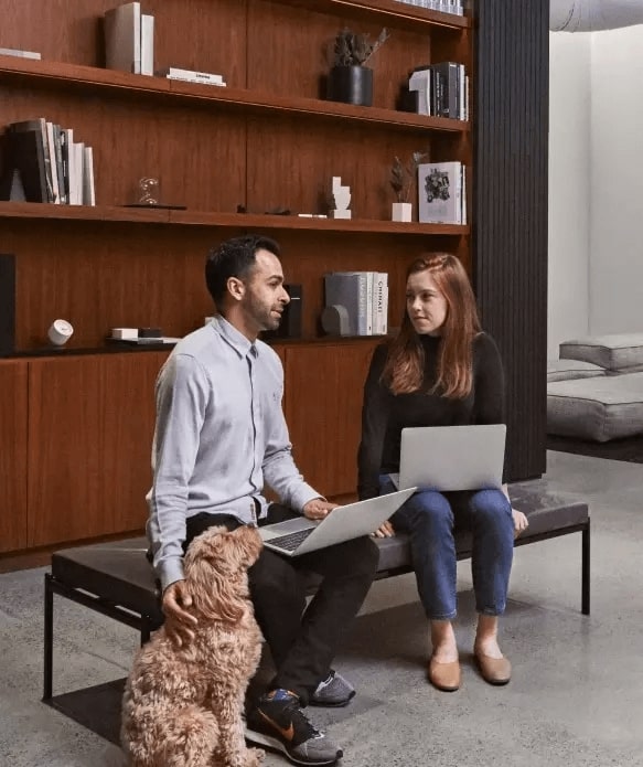 man and woman on a couch talking and a dog watching them